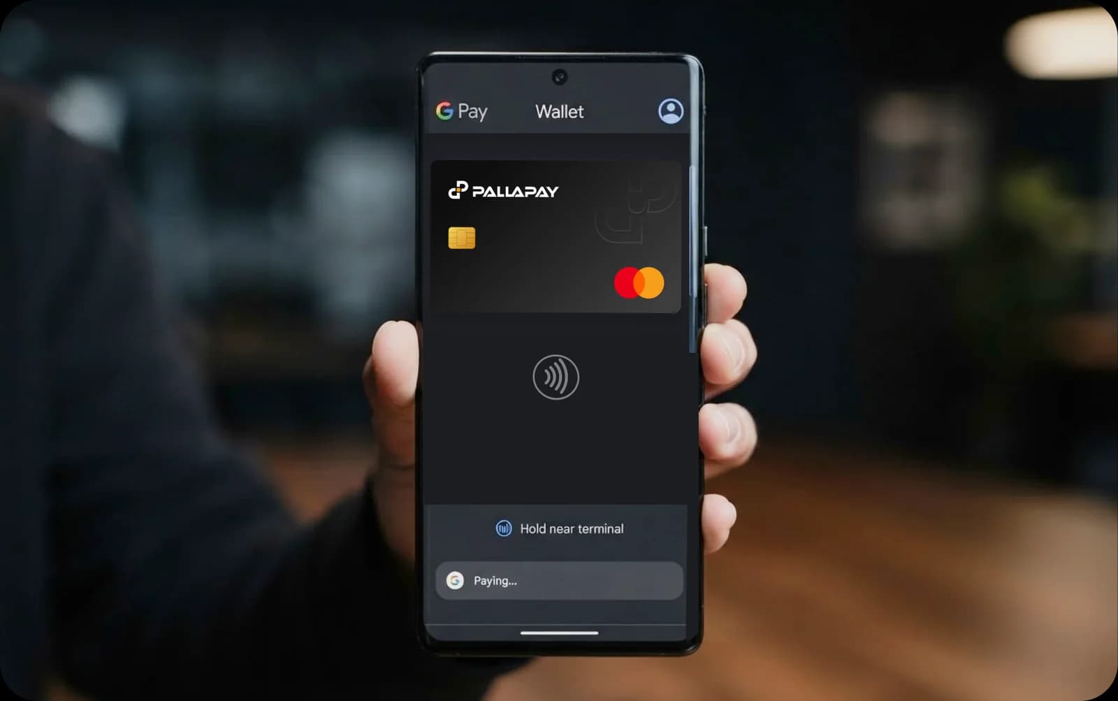 Hand holding an Android phone showing a Pallapay crypto card in Google Pay